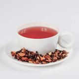 Crimson Punch tea in a cup with loose leaf tea in a saucer