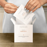 Tavalon Serenity herbal tea packaging with hands opening it on a wooden surface.