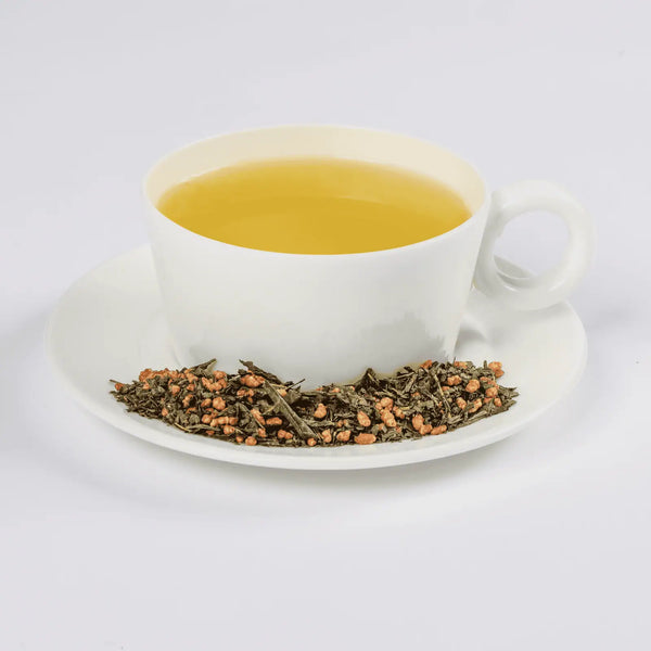Genmaicha tea in a white teacup with loose leaf tea in a saucer