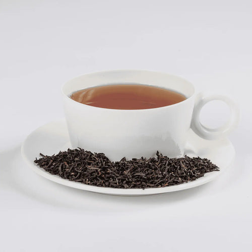 NYC Breakfast tea in a white teacup with loose leaf tea in a saucer