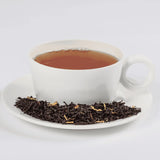 Peachy Oolong tea in a white teacup with loose leaf tea in a saucer