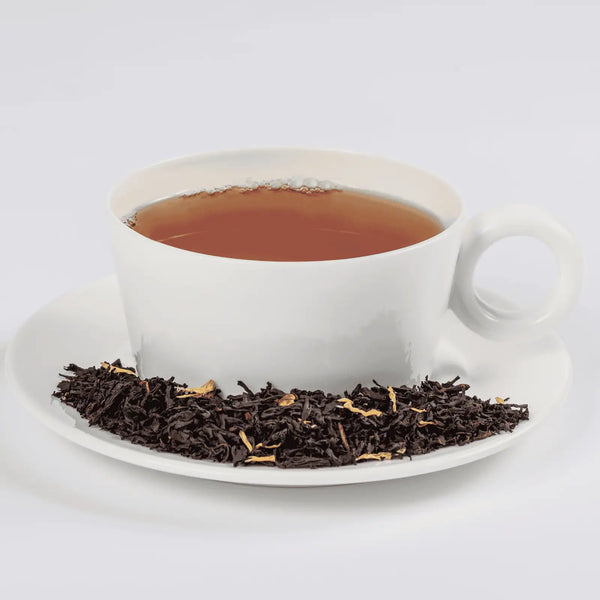 Peachy Oolong tea in a white teacup with loose leaf tea in a saucer